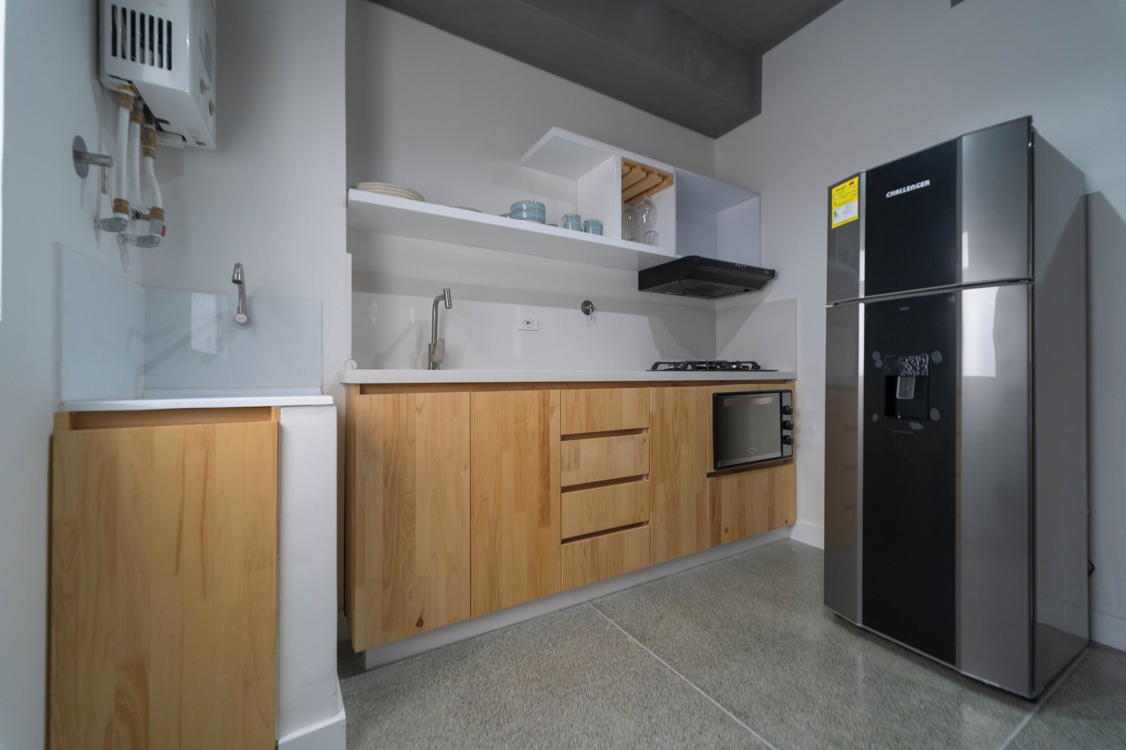 A modern kitchen with wooden cabinets, a stainless steel refrigerator, and a built-in oven.