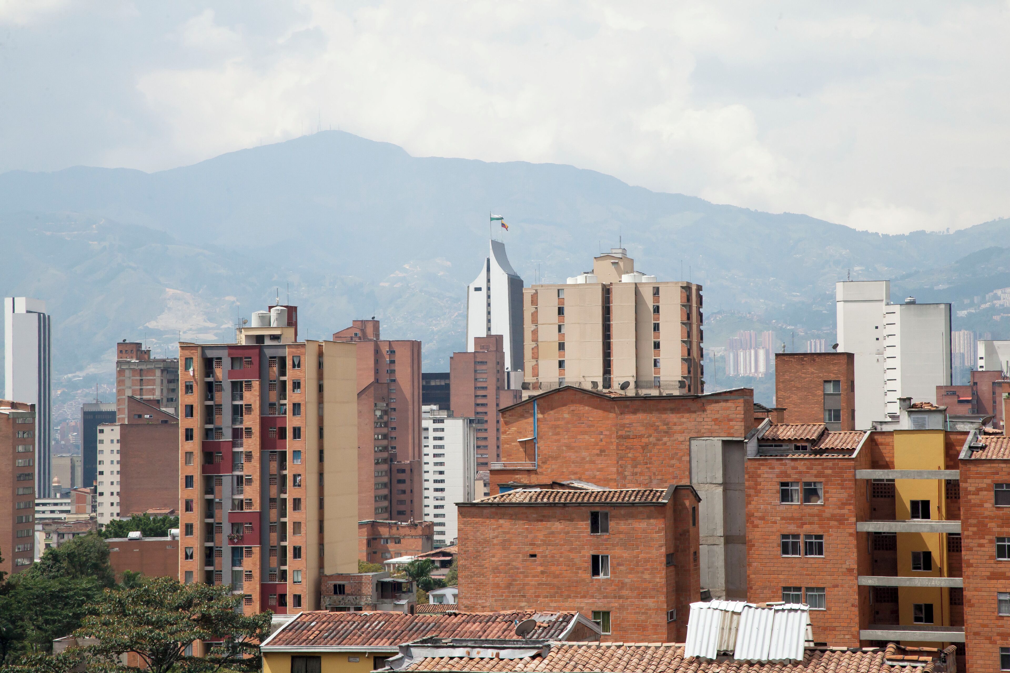 Un paisaje urbano con una mezcla de edificios modernos y tradicionales, incluyendo un rascacielos blanco destacado y varias construcciones de ladrillo rojo.