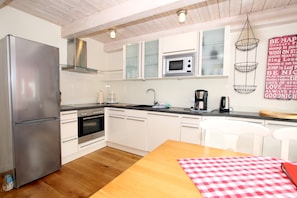 Une cuisine moderne avec des meubles blancs, des appareils en acier inoxydable et une table à manger en bois.