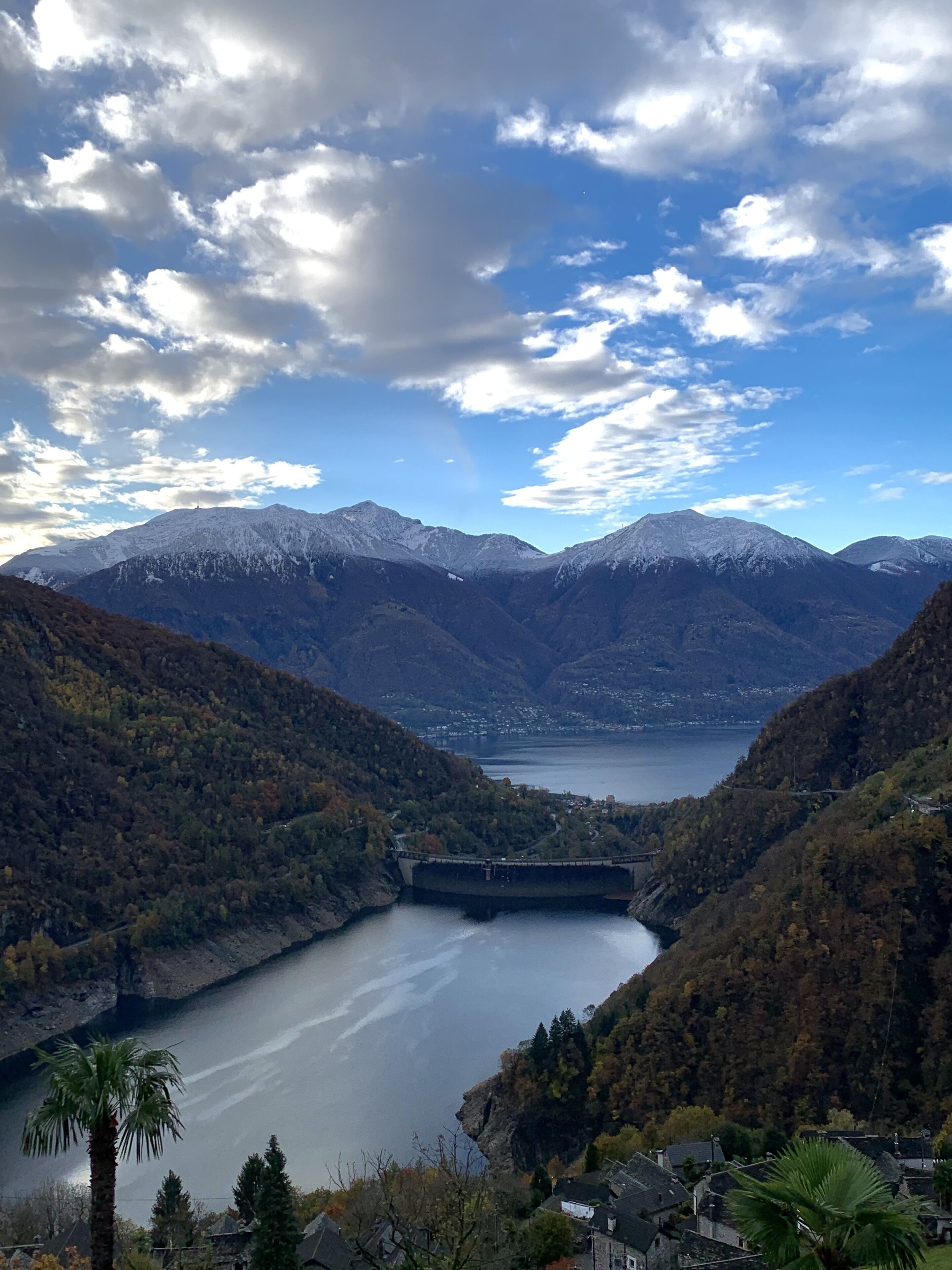 Un paysage montagneux avec un lac, un pont et une ville située dans la vallée.