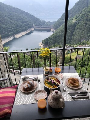 Une table dressée avec des aliments pour le petit-déjeuner, donnant sur un lac entouré de collines.