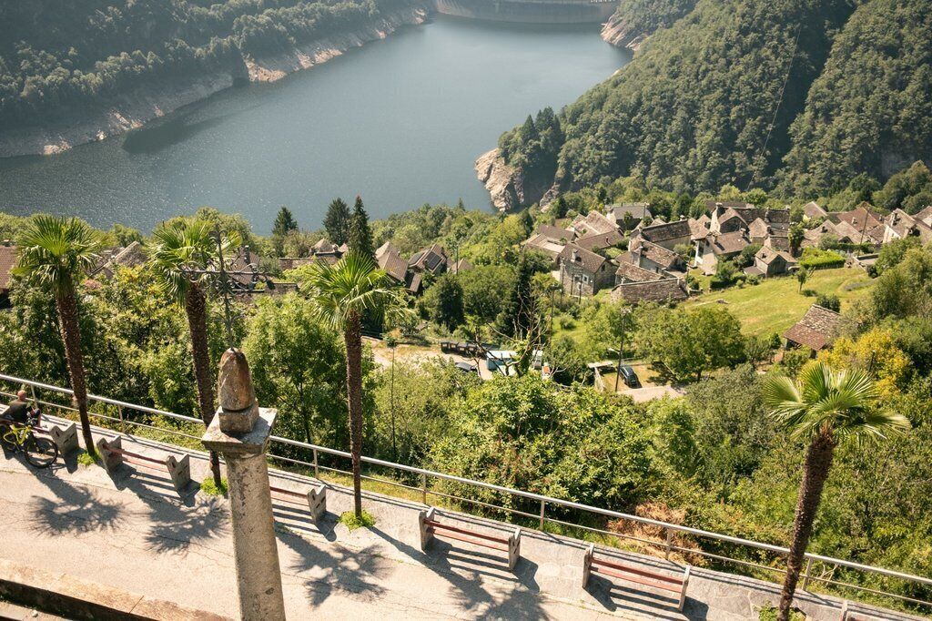 A scenic overlook with a view of a village, a body of water, and a stone monument.