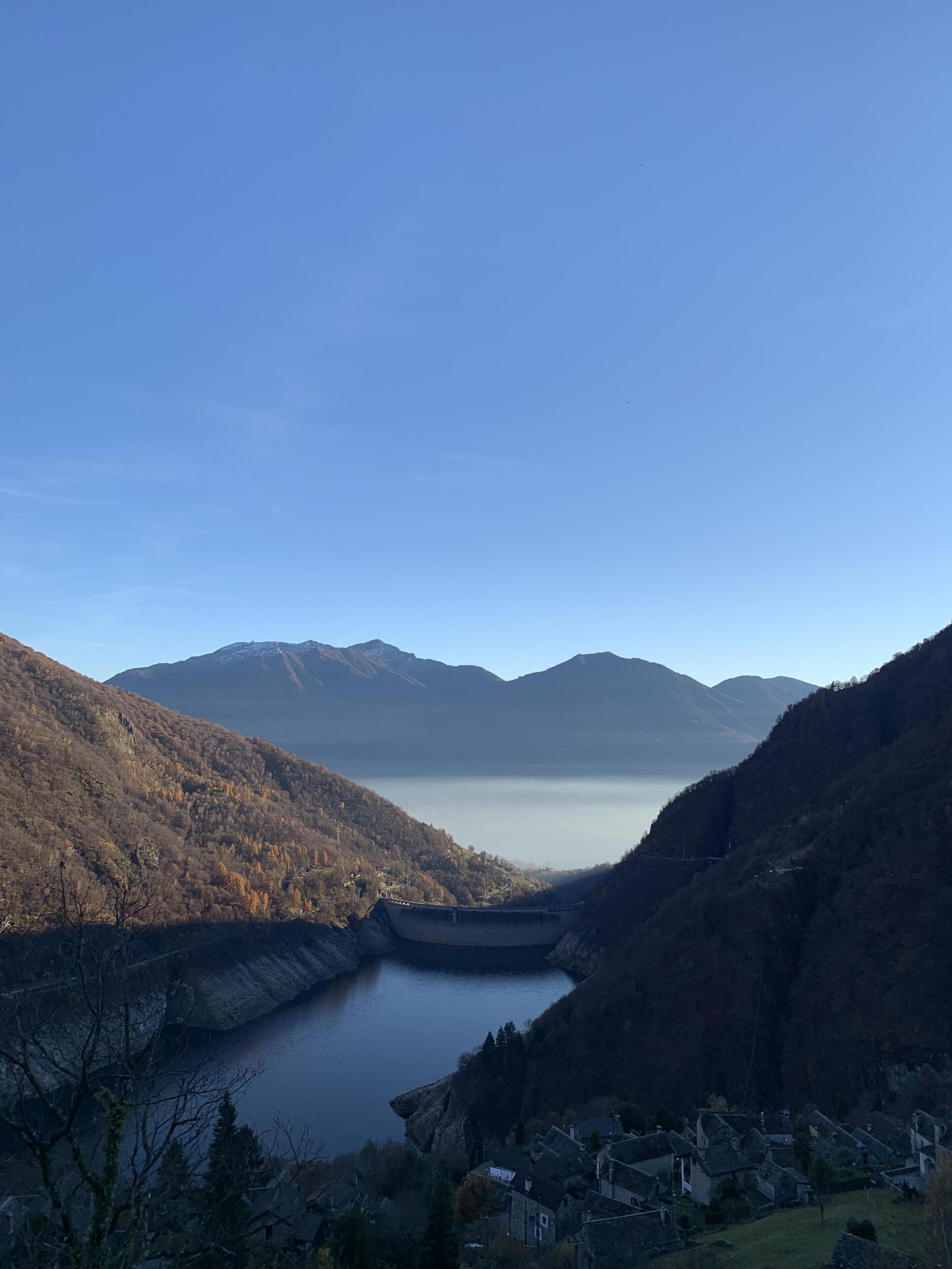 A serene landscape with a lake, mountains, and a small village.