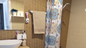 Un baño con lavamanos, espejo, inodoro y zona de ducha.