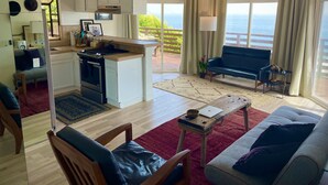 A modern living room with a sofa, a coffee table, and a kitchen area with a stove and cabinets. - OCEAN VIEW BUNGALOW - MALIBU, CA (Malibu)
