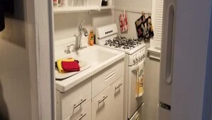 Une cuisine de taille réduite, équipée d’un évier, d’une cuisinière et de placards.