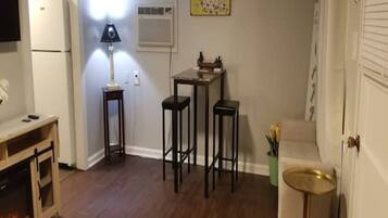 A compact living space with a kitchenette, a dining area with stools, a small table, and a decorative lamp.