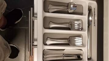 Un cajón con cubiertos, incluyendo cuchara, tenedor y cuchillo.