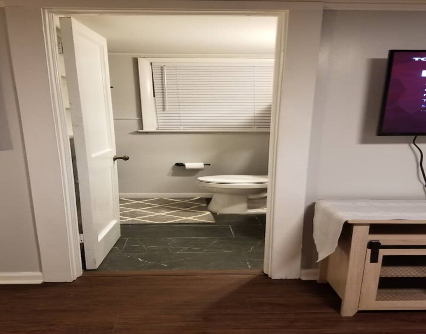 A bathroom with a toilet, a towel rack, and a window with blinds.
