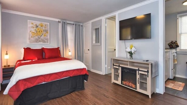 Une chambre d’hôtel avec un grand lit, un téléviseur à écran plat, une cheminée et un tableau au mur.
