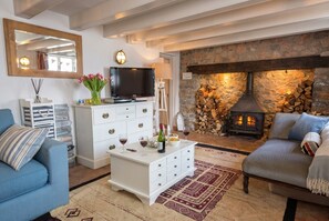 A living room with a stone fireplace, a television, a white cabinet, and a blue sofa.
