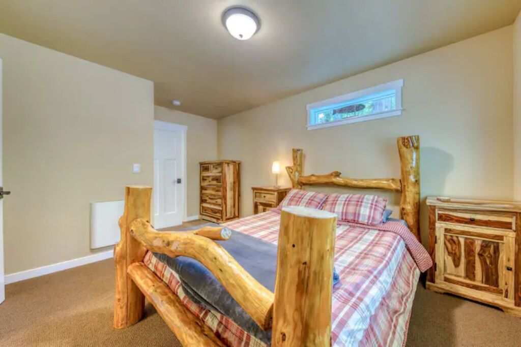 Une chambre à coucher avec un lit en bois, une couverture à carreaux, une table de chevet et une commode avec un miroir.