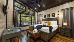A bedroom with a large bed, a desk, a bench, and a ceiling fan.