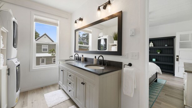 A modern bathroom with a large mirror, dual sinks, and a window providing a view of the outside.