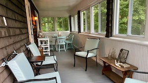 Eine überdachte Veranda mit Holzwänden, einem Tisch mit Stühlen und einer Bank.