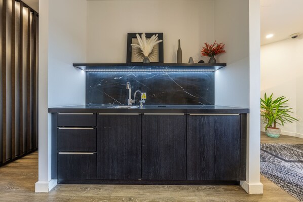 Uma cozinha moderna com armário de madeira escura, pia de aço inoxidável e backsplash de mármore.