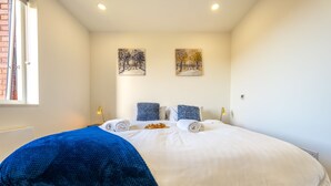 Una cama bien hecha con ropa de cama blanca y azul, dos almohadas y una manta azul.