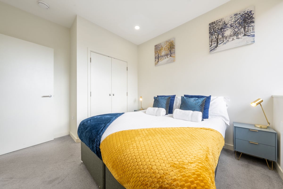 Un dormitorio con cama, mesitas de noche, una puerta y decoración en la pared.