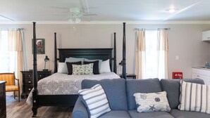 Une chambre à coucher avec un lit à baldaquin, un canapé gris et un ventilateur de plafond.