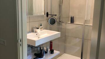 Une salle de bain moderne avec une douche à parois de verre, un lavabo blanc et un miroir.