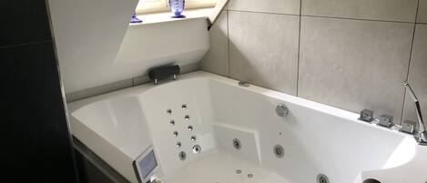 Un baño moderno con una bañera independiente, un ventanal con vistas a zonas verdes y un calentador integrado.