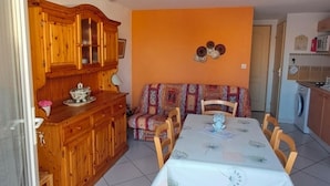 Een eetgedeelte met een tafel, stoelen, een houten kast, een bank en een balkon.