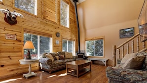 Ein gemütliches Blockhaus-Interieur mit Holzwänden, einem Kamin, einer Couch und einer Bank.