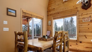 Ein Holzinterieur mit Esstisch und Stühlen, großen Fenstern und einer Dekoration mit einem Bärenkopf.
