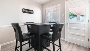 A dining area with a black table and chairs, a sign reading "Bon Appetit," and a white door with a window.