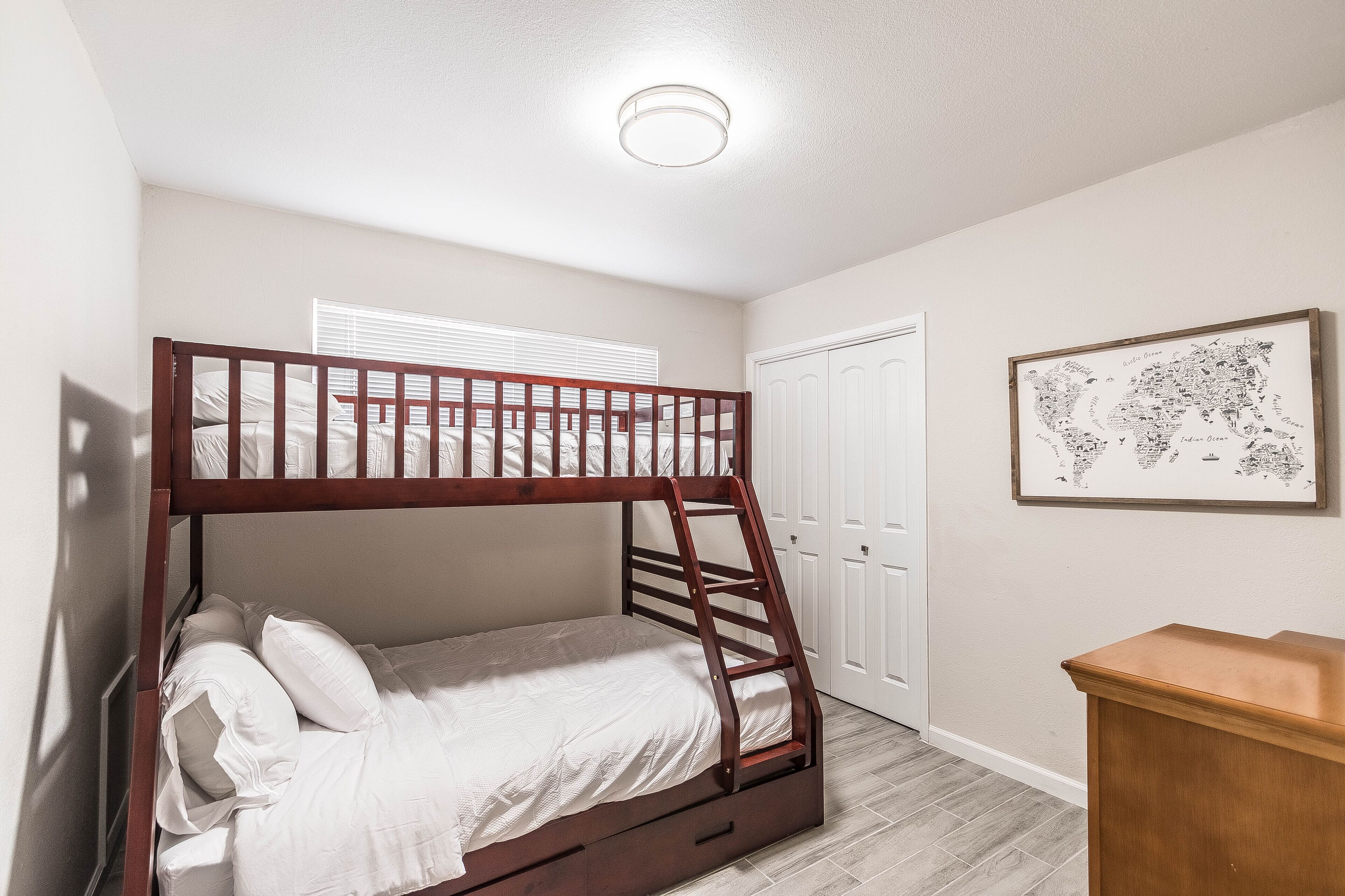 A bunk bed with a ladder, a white door, and a framed map on the wall.