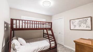 A bunk bed with a ladder, a white door, and a framed map on the wall.