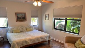 Quarto com cama, cadeira, mesa de cabeceira e ventilador de teto.