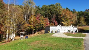 A house with a driveway leading to a garage, surrounded by a forest with autumn-colored trees. - Mi Casa is your home Beautiful views (Biltmore lakes)