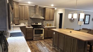 A modern kitchen with wooden cabinets, a stainless steel stove, and a wooden island. - Mi Casa is your home Beautiful views (Biltmore lakes)