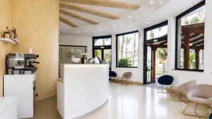 A modern reception area with a coffee machine, seating, and large windows. - Oasi Park Hotel (Mascali)