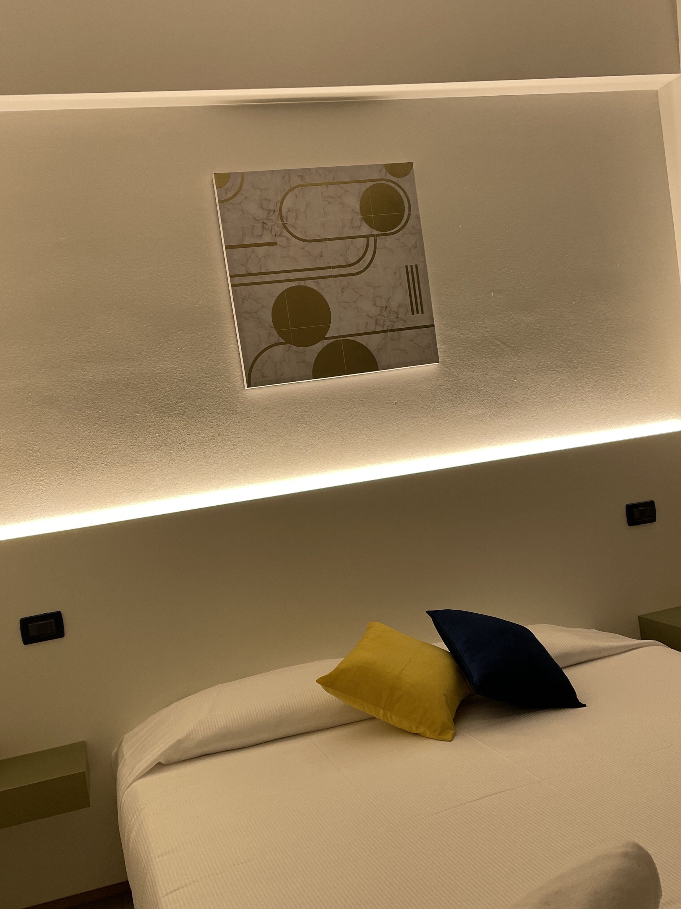 Una habitación de hotel con cama, lámpara de pared y un panel decorativo.