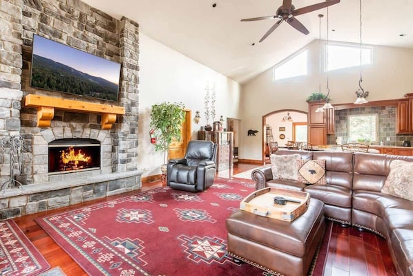 A stone fireplace, leather sofa, and a television mounted on the wall.