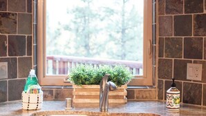 A kitchen with a stone backsplash, a window with a view of greenery, a wooden countertop, and a stainless steel faucet. - Canyon Crest Lodge. Hot Tub, Game Room, and Views. (Big Bear Lake)