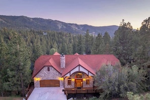 A stone house with a red roof, a wooden deck, and a garage.