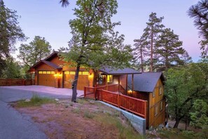 Une cabane en rondins avec un porche, un garage et une petite terrasse.