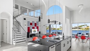 Una cocina moderna con una isla central, una escalera y vistas al exterior.