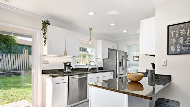 Una cocina moderna con armarios blancos, electrodomésticos de acero inoxidable y una isla grande con un lavabo.