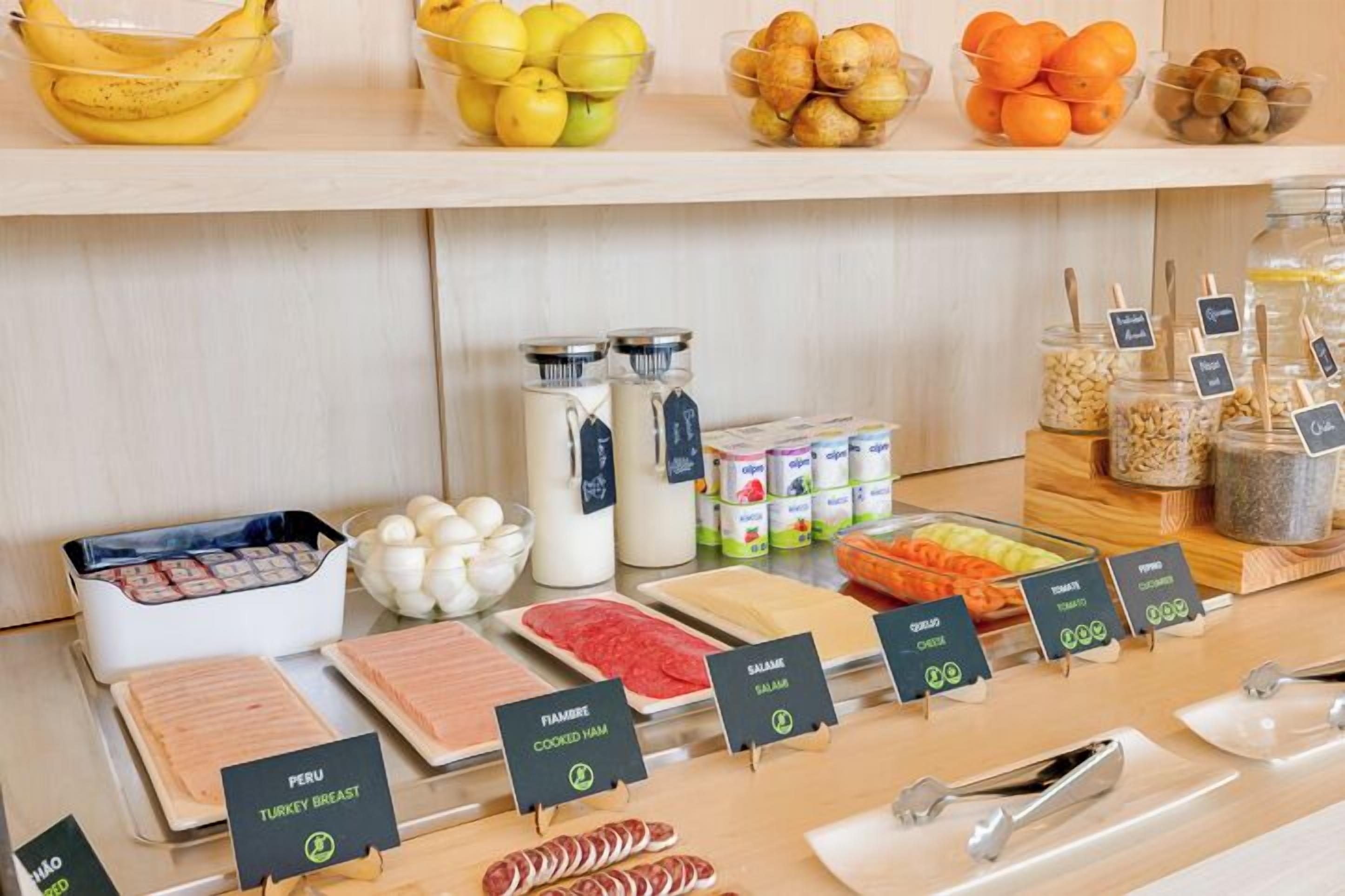 A deli counter with various meats, cheeses, and fruits.