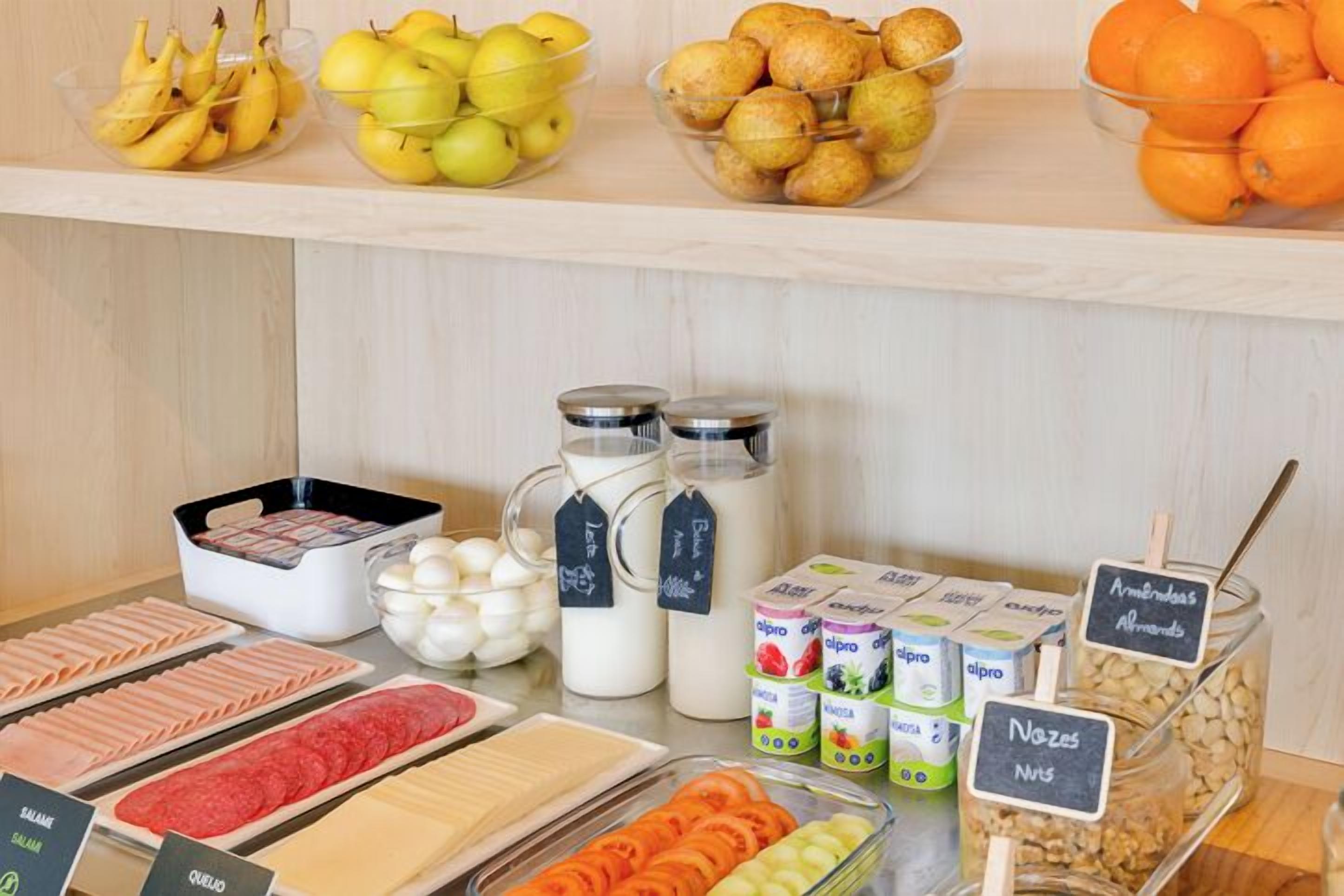 Un bufé de desayuno con una variedad de alimentos, incluyendo frutas, productos lácteos y carnes.