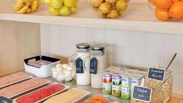 Un bufé de desayuno con una variedad de alimentos, incluyendo frutas, productos lácteos y carnes.