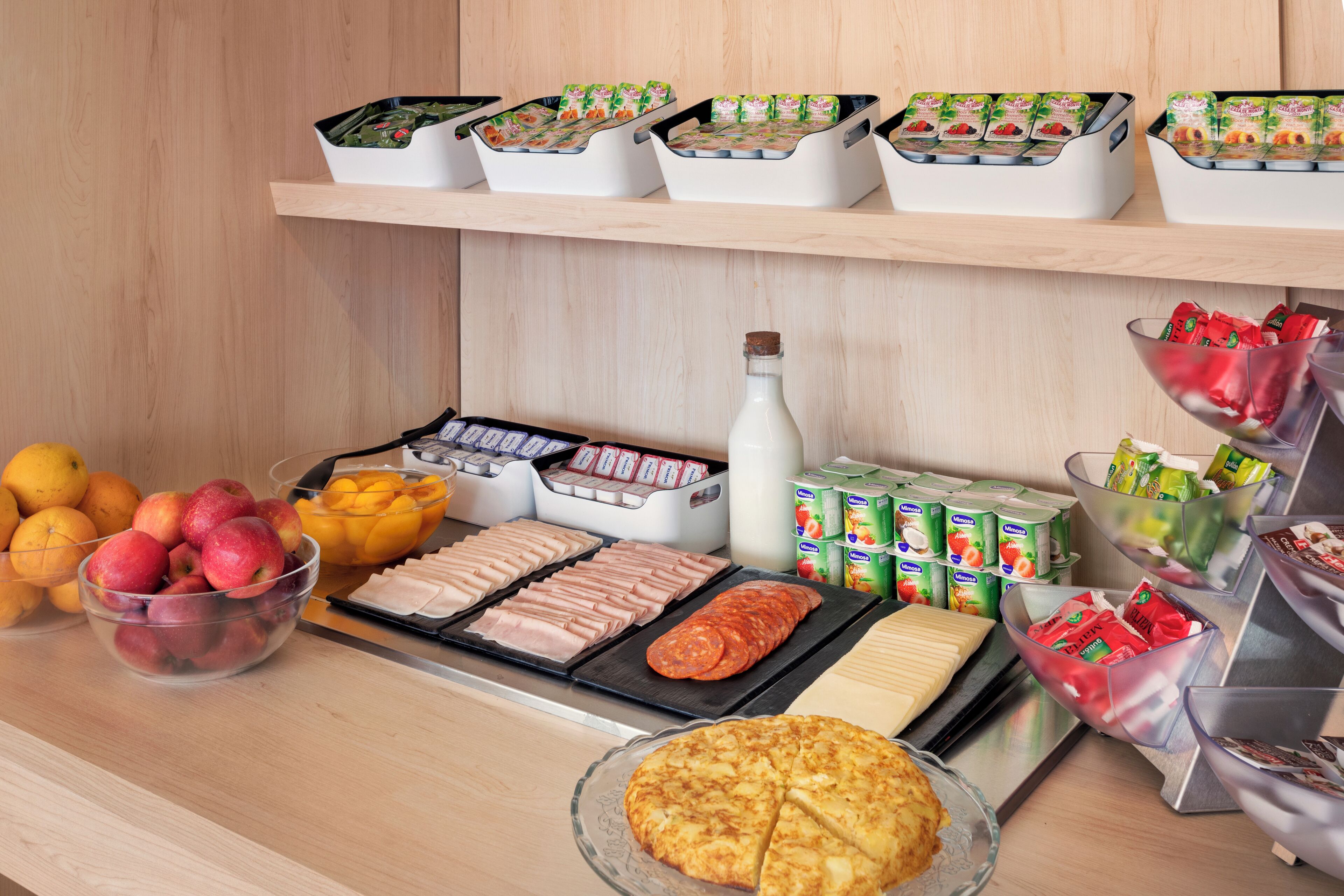 Un buffet proposant une variété de plats, notamment des fruits, de la viande et des produits laitiers.