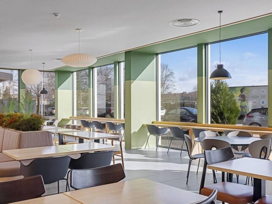 A modern cafe with large windows, seating areas, and pendant lighting.