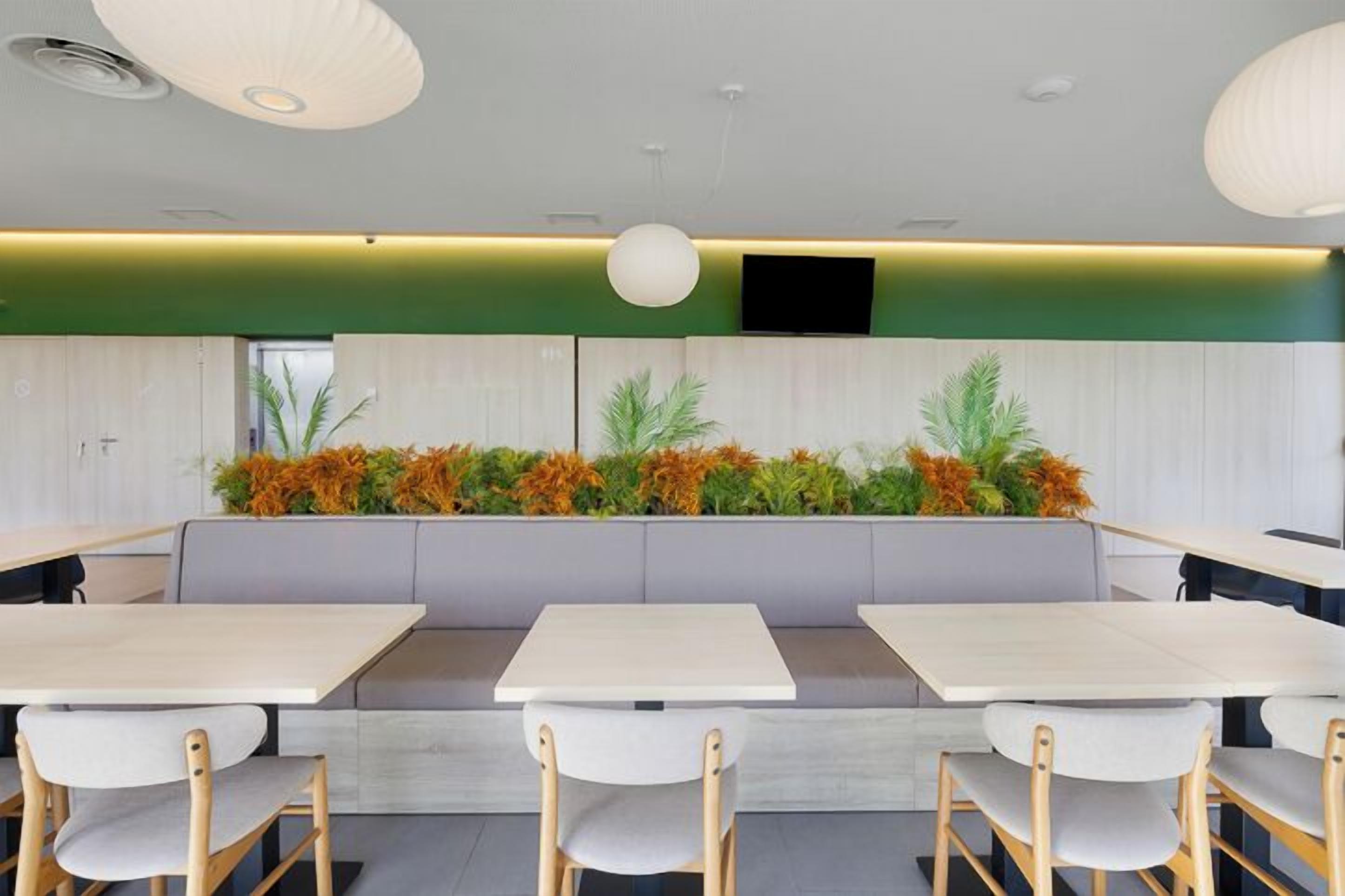 Un espace repas moderne avec un long banc, plusieurs tables et des chaises.