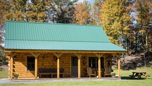 Eine Blockhütte mit grüner Dach und einer Veranda mit Sitzgelegenheiten sowie einem Picknicktisch.