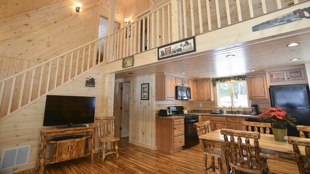 Ein geräumiges Holzhaus-Interieur mit Essbereich, Küche und einer Treppe, die zu einem Schlafboden führt.